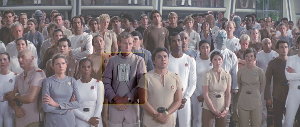 Rec. room briefing scene from ST:TMP with a crew member extra wearing the enviro tech suit costume.